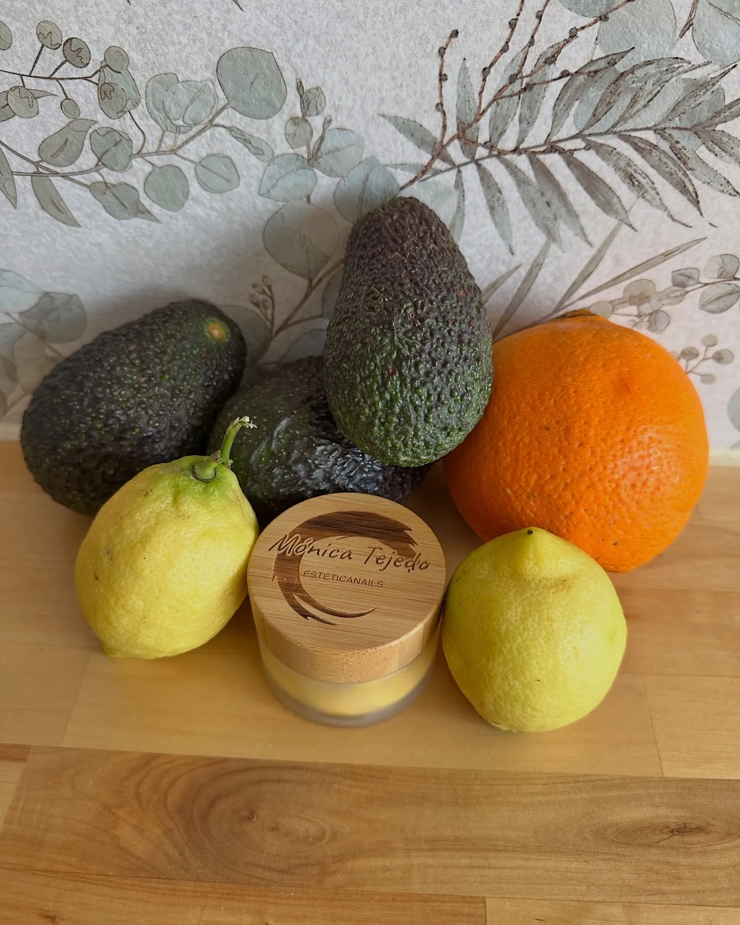 Crema facial artesanal de Mónica junto a aguacates, limones y una naranja